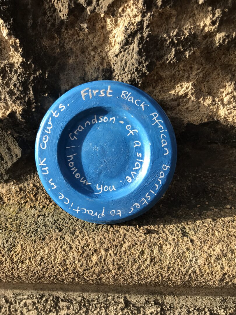 Blue plate set against a wall, with round writings following the edges. 