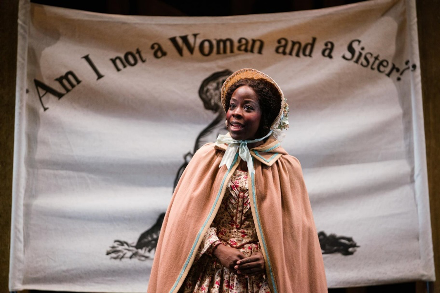 Woman with a hood standing in front of a banner
