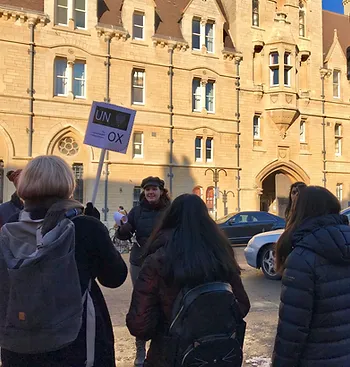 Image of a person guiding a group in front of an ancient building. 