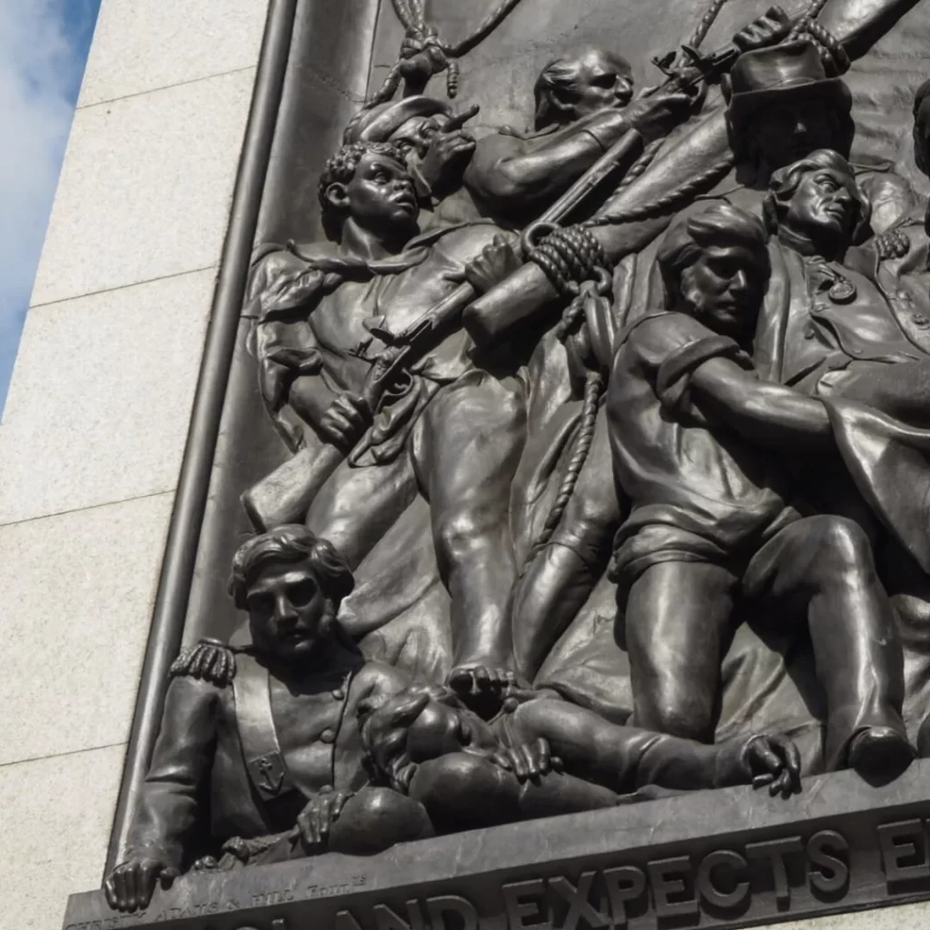 Detail of a bronze sculpture panel depicting severail sailors in a heroic posture.