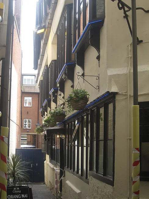 Photo of a narrow city street with old building and flower baskets. 