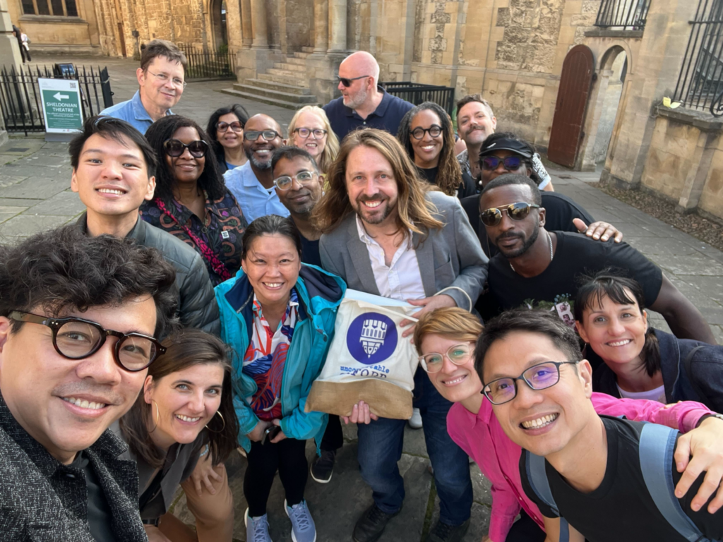 A group of people gather around an Uncomfortable Oxford Tour Guide and smile while taking a photo.