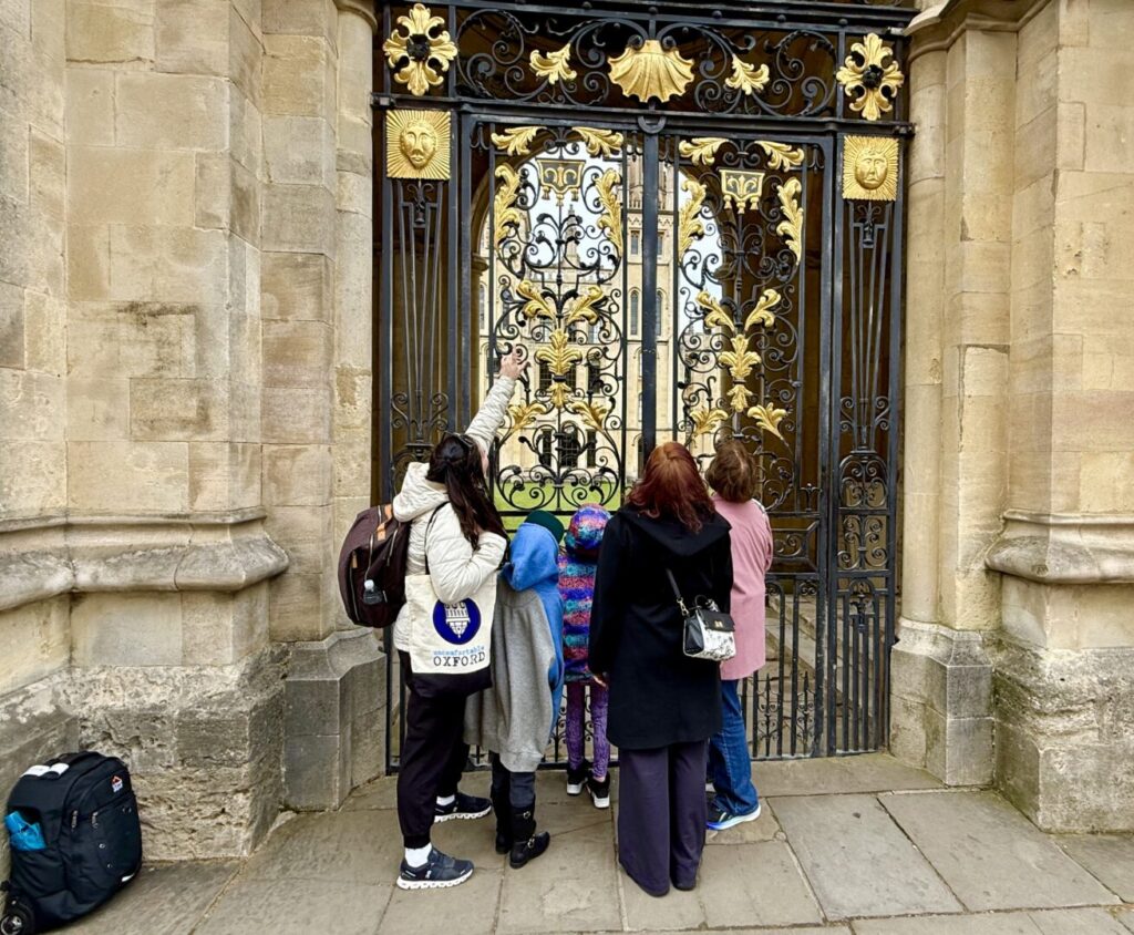 An Uncomfortable Oxford tour guide shows a detail to an onlooking audience at All Souls College.