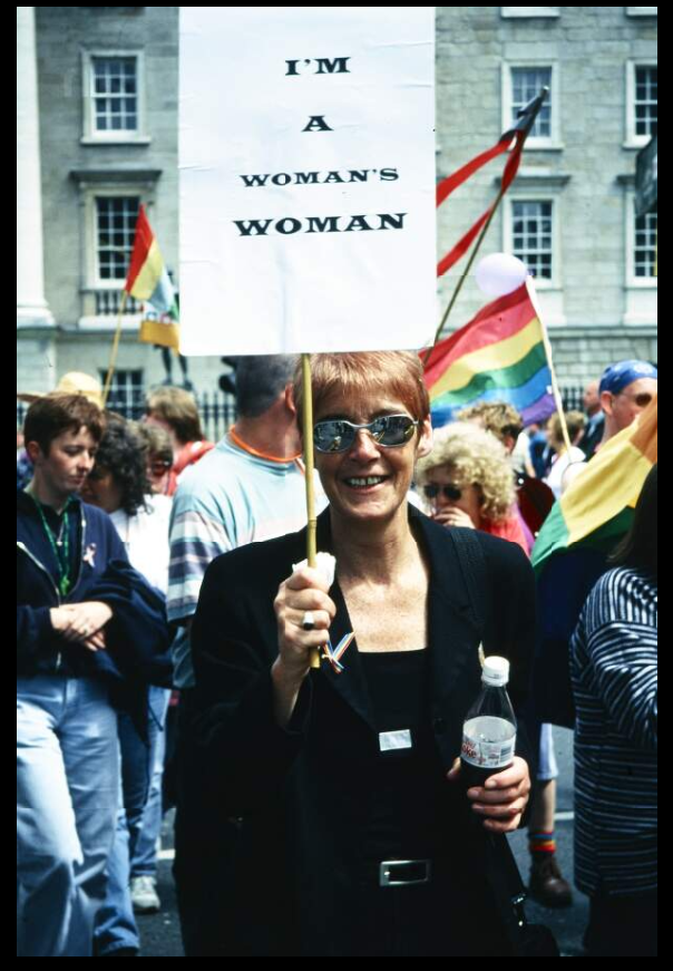A woman holding a sign that says 'I'm a Woman's Woman at a pride event